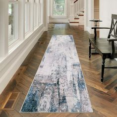 a long rug in the middle of a room with wooden floors and chairs on either side