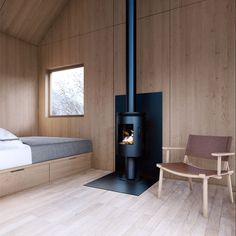 a room with a bed, chair and wood burning stove in the middle of it