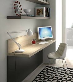 a computer monitor sitting on top of a wooden desk next to a lamp and bookshelf