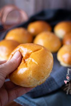 a person is holding a bun in front of some rolls on a blue towel and wooden table