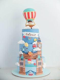 a three tiered cake decorated with an image of a hot air balloon in the sky