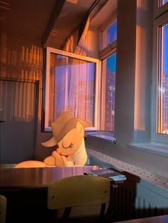 a stuffed animal sitting at a table in front of a window with the city outside