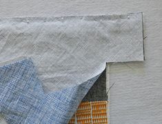 an orange and blue piece of fabric on top of a white wall next to a patch of cloth