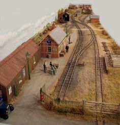 an old model train station with people on the tracks