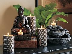 a buddha statue sitting on top of a table next to candles