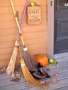 two brooms sitting on top of a pile of leaves next to a house door