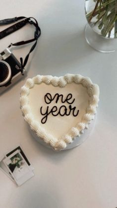 a heart shaped cake with the words one year written on it next to a camera