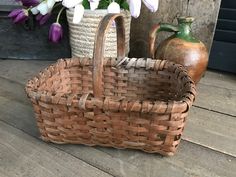 a wicker basket sitting on top of a wooden floor next to vases and flowers