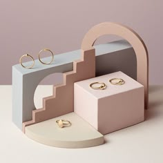 two wedding rings are sitting on top of an arch - shaped display case, which is also made out of cardboard