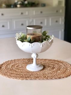 a white bowl filled with flowers on top of a table next to a candle holder