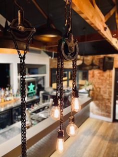 several lights hanging from the ceiling in a restaurant or bar with wood flooring and exposed beams