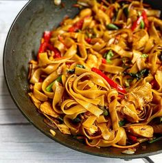 a pan filled with pasta and vegetables on top of a wooden table