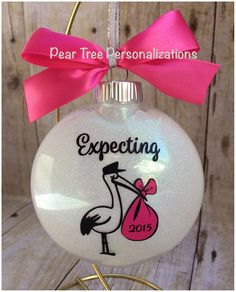 a glass ornament with a pink bow on it and the words expecting 2013