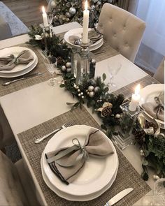 a table set for christmas dinner with place settings and candles in the centerpieces