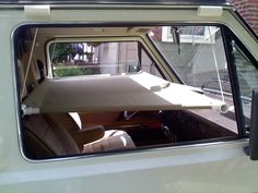 the interior of an old car with its sunroof open and it's seat folded down