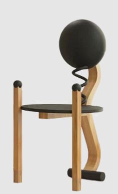 an unusual chair with a black seat and wooden legs, sitting on top of a white surface