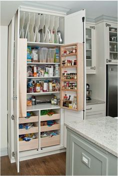 an open refrigerator in a white kitchen with lots of cupboards and drawers on the door