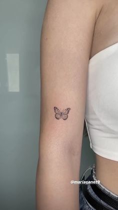 a woman's arm with a small butterfly tattoo on the back of her left arm