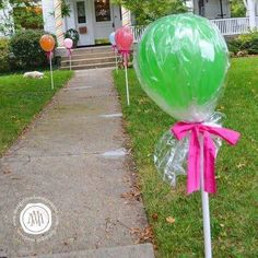 green and pink lollipops in front of a house