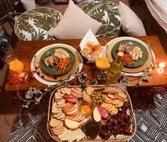 a wooden table topped with plates and bowls filled with different types of food next to candles