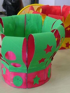 two paper crowns sitting on top of a table next to each other with stars and shapes painted on them