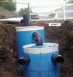 two large blue barrels sitting next to each other on the ground in front of a fence