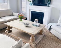 a living room with white couches and a coffee table in front of a fireplace