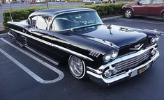 an old black car parked in a parking lot