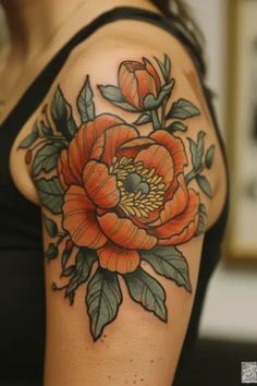 a woman's arm with an orange flower and leaves tattoo on her left shoulder