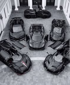 four black sports cars parked in front of a white building with columns on the side