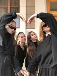 four young women in nun costumes making a heart with their hands