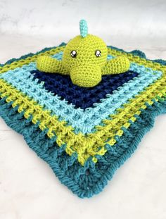 a crocheted blanket with a stuffed animal on top