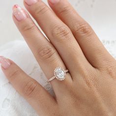 a woman's hand with a diamond ring on top of her finger and pink manicured nails