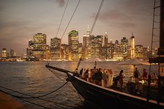 a group of people sitting on top of a boat in the water near a city