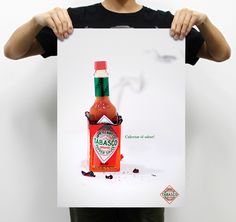 a person holding up a poster with a hot sauce bottle on it