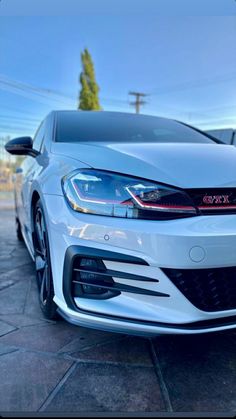 the front end of a white car parked in a parking lot