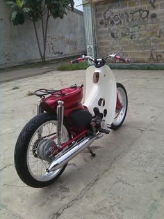 a red and white motorcycle parked in front of a building with graffiti on the walls