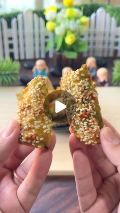 two hands holding up some food with sesame sprinkles on top of it