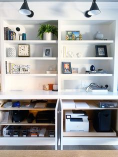 two white shelves filled with books and other items on top of each other in a room