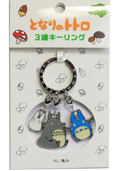 two key chains with cartoon characters on them in front of a card board that says hello kitty and totoro