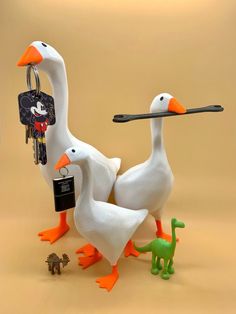 two white ducks with orange beaks are holding keys to each other and an alligator is standing next to them