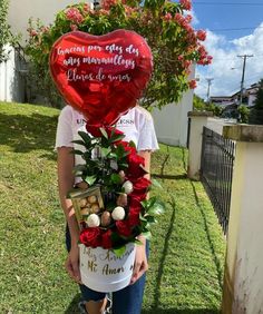 a woman holding a heart shaped balloon with flowers in it