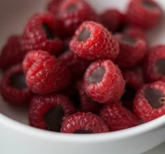 some raspberries are in a white bowl