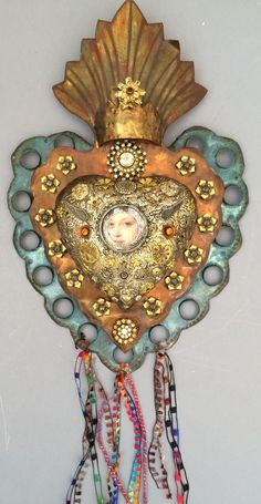 a decorative wall hanging with beads and an ornate face on it's center piece