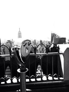 a black and white photo of a parking meter in front of a cityscape