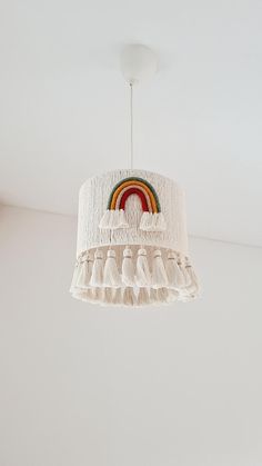 a white chandelier hanging from the ceiling with a rainbow painted on it and tassels