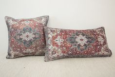 two red and blue pillows sitting on top of a white bed next to each other