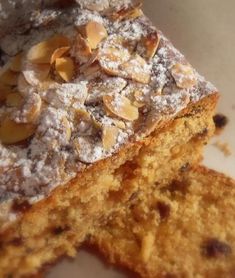 two pieces of cake with powdered sugar and nuts on top sitting on a plate