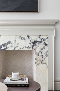 a marble fireplace mantel in a living room with a black and white painting on the wall