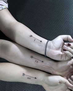 two people with matching tattoos on their arms holding hands and touching each other's palms